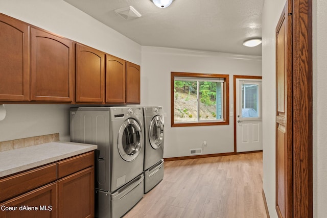 1358 S Starlight Dr, Coeur Dalene, ID 83814 - laundry area featuring visible vents, cabinet space, baseboards, separate washer and dryer, and light wood-style flooring