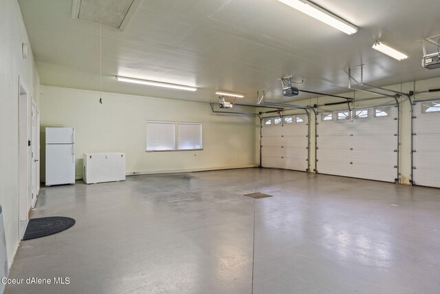 1358 S Starlight Dr, Coeur Dalene, ID 83814 - garage featuring a garage door opener, freestanding refrigerator, and refrigerator
