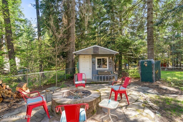 view of outbuilding featuring fence, an outbuilding, and a fire pit