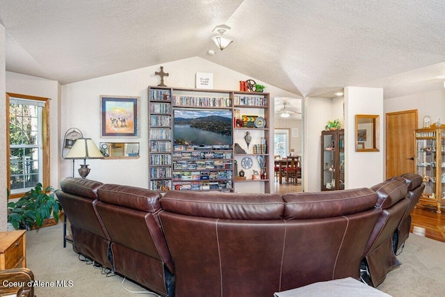 living room with vaulted ceiling, a textured ceiling, and light colored carpet