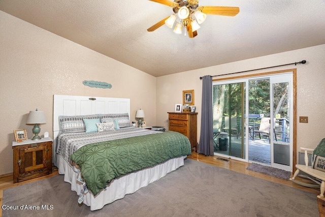 bedroom featuring wood finished floors, access to exterior, ceiling fan, a textured ceiling, and vaulted ceiling