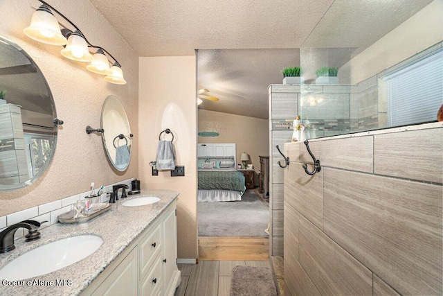 full bath with a sink, a textured ceiling, walk in shower, and ensuite bath