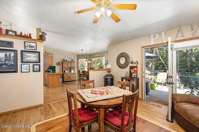 dining area with a textured ceiling, visible vents, ceiling fan, and light wood finished floors