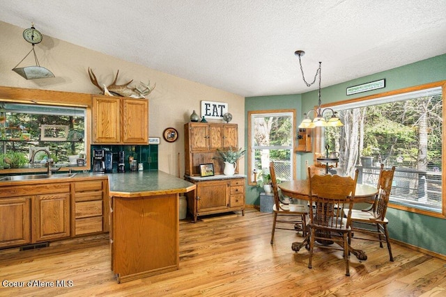 kitchen with a sink, light wood-style floors, brown cabinets, and a textured ceiling