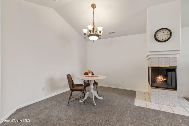 dining room featuring visible vents, a tile fireplace, carpet flooring, a notable chandelier, and vaulted ceiling