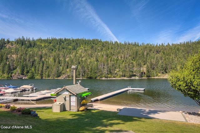 dock area featuring a lawn, a water view, and a wooded view