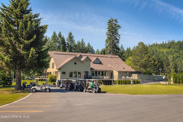 view of community with uncovered parking and a yard
