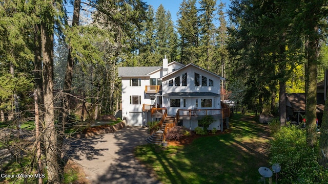 view of front of property featuring stairs, a garage, a front yard, concrete driveway, and a balcony