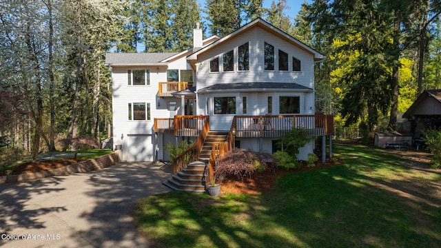 view of front of house with aphalt driveway, a balcony, a chimney, stairs, and an attached garage