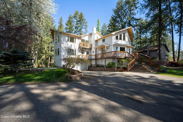 view of front of house with an attached garage, driveway, and stairs