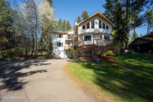 view of front facade featuring driveway, a wooden deck, a garage, stairway, and a front lawn