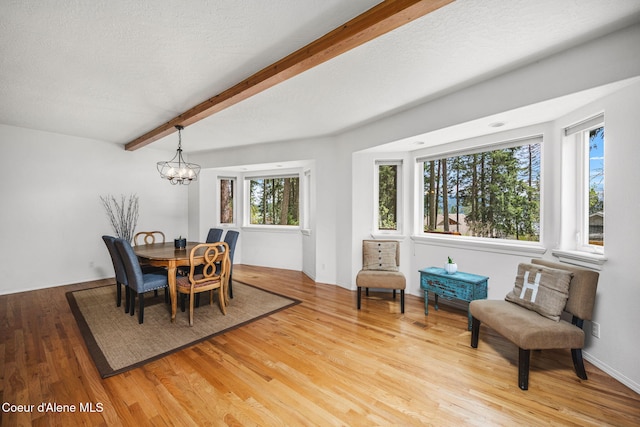 dining area featuring a textured ceiling, light wood-type flooring, beam ceiling, and a notable chandelier