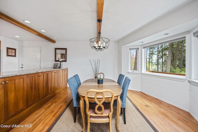 dining room featuring beamed ceiling, a chandelier, baseboards, and light wood-style floors