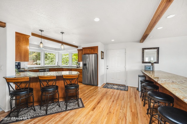 kitchen featuring a sink, a peninsula, beam ceiling, and stainless steel appliances