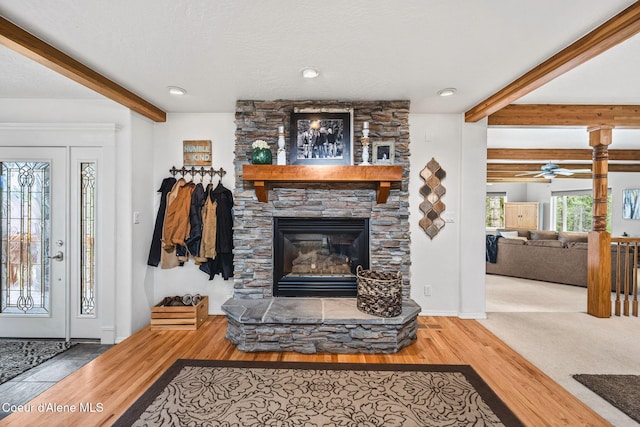 living room featuring a fireplace, beam ceiling, and wood finished floors