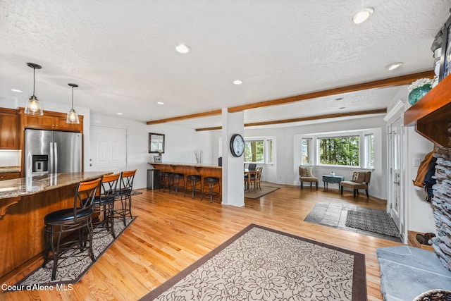 living area featuring light wood-style floors, recessed lighting, a textured ceiling, and bar