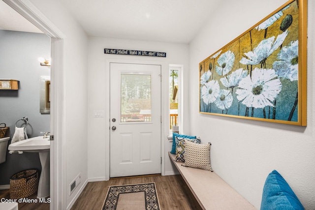 doorway featuring baseboards, wood finished floors, and visible vents