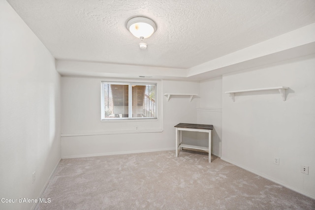 carpeted empty room featuring baseboards and a textured ceiling