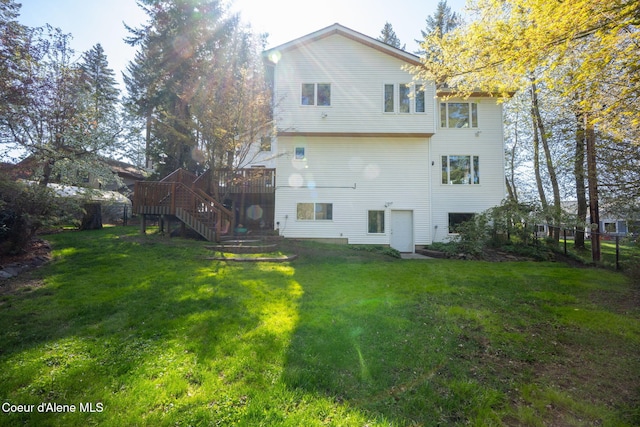 back of house with stairway, a lawn, fence, and a wooden deck