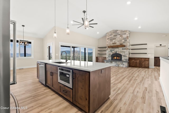 kitchen with ceiling fan, vaulted ceiling, dishwasher, a sink, and light wood-style flooring