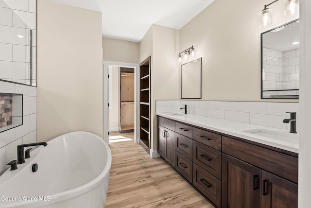 bathroom featuring double vanity, a freestanding tub, a sink, and wood finished floors