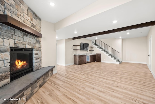 unfurnished living room with baseboards, a stone fireplace, recessed lighting, and light wood-style flooring