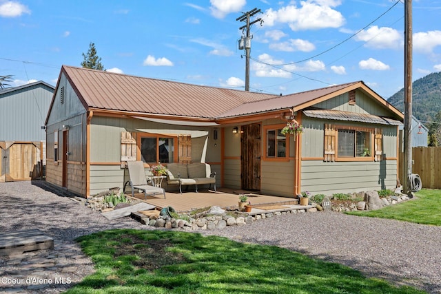 view of front facade featuring outdoor lounge area, fence, a deck, and metal roof