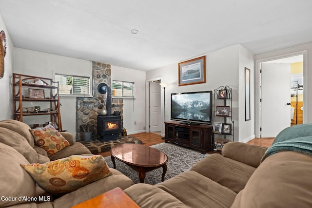 living room featuring baseboards, wood finished floors, and a wood stove