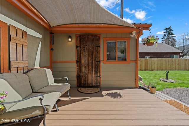 wooden terrace featuring a lawn and fence