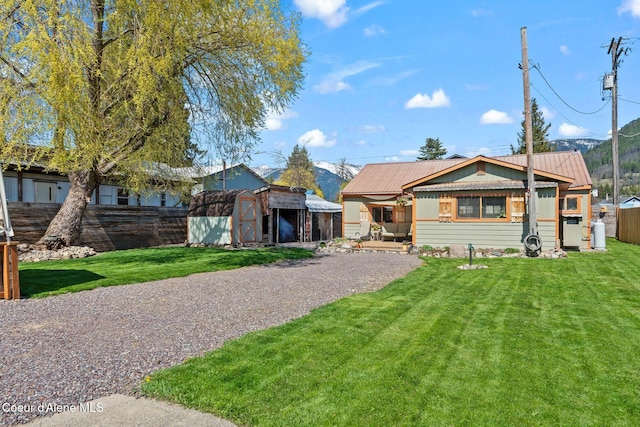 view of front of property featuring an outbuilding, fence, a storage shed, and a front yard