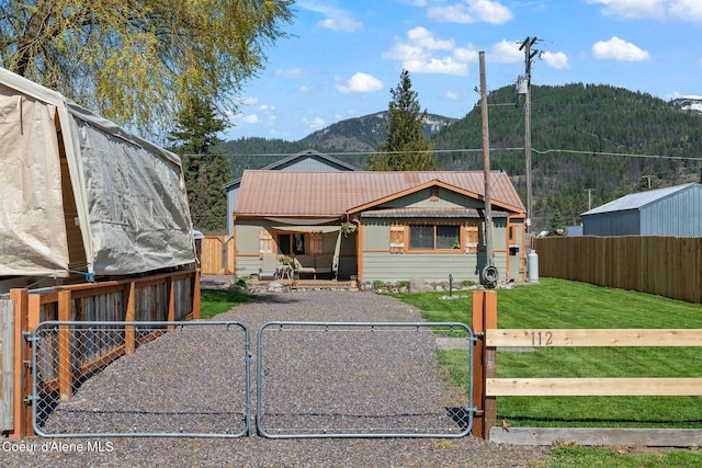 bungalow-style home featuring a fenced front yard, a front yard, a gate, a mountain view, and metal roof