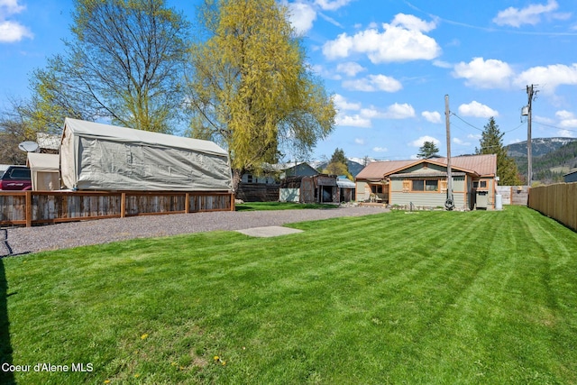 view of yard featuring a fenced backyard, a storage unit, and an outdoor structure