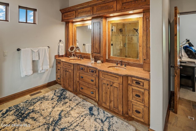 bathroom with baseboards, a sink, double vanity, and a shower stall