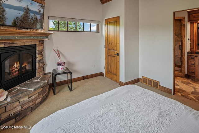 carpeted bedroom featuring visible vents, baseboards, and a stone fireplace