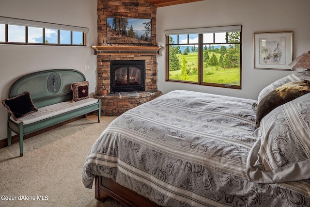 bedroom with a stone fireplace and carpet