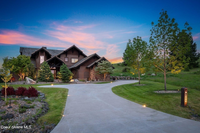 log home with curved driveway and a yard