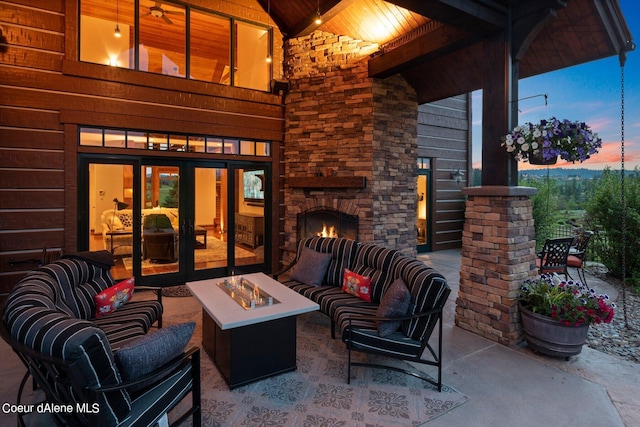 patio terrace at dusk featuring an outdoor living space with a fireplace