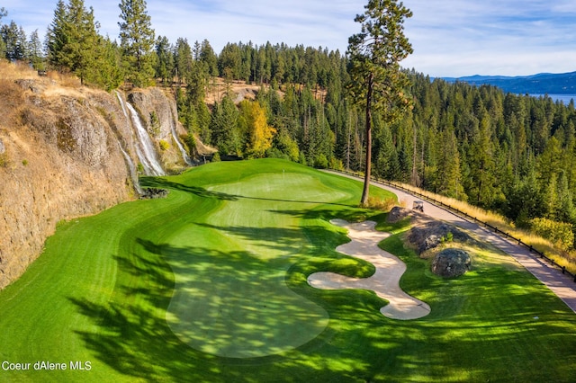 view of home's community with a wooded view, a mountain view, and golf course view