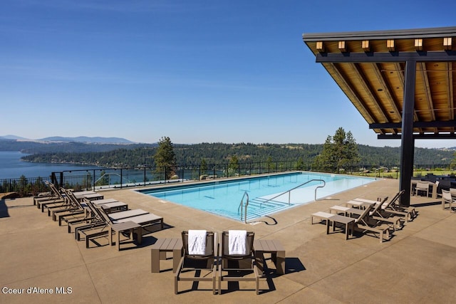 community pool with fence, a patio area, and a water and mountain view