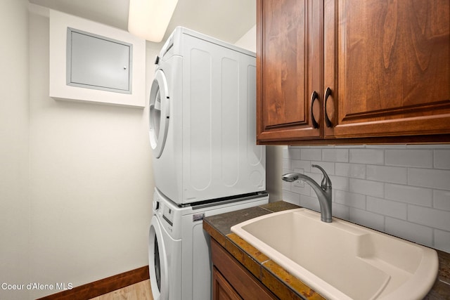2151 N Main St # 226, Coeur Dalene, ID 83814 - clothes washing area with baseboards, a sink, cabinet space, and stacked washing maching and dryer