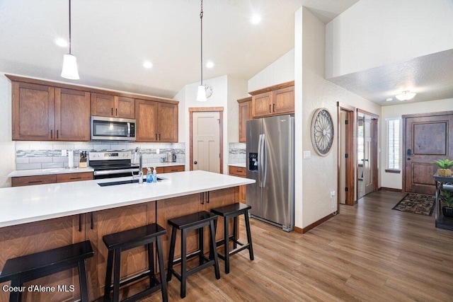 635 E Valley St, Oldtown, ID 83822 - kitchen featuring decorative backsplash, wood finished floors, a sink, vaulted ceiling, and stainless steel appliances