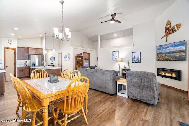 635 E Valley St, Oldtown, ID 83822 - dining room with a glass covered fireplace, ceiling fan with notable chandelier, recessed lighting, wood finished floors, and vaulted ceiling