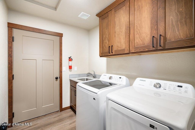 635 E Valley St, Oldtown, ID 83822 - laundry room featuring visible vents, cabinet space, a sink, light wood-style flooring, and washer and clothes dryer