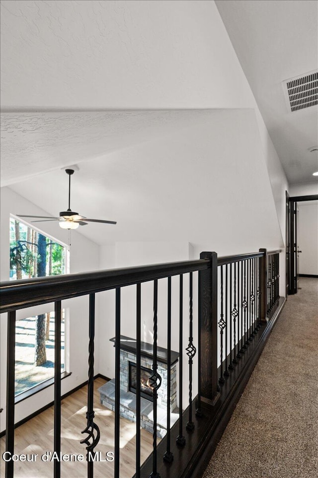 hallway featuring visible vents, wood finished floors, and lofted ceiling