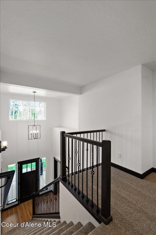 interior space with baseboards, a textured ceiling, and a notable chandelier