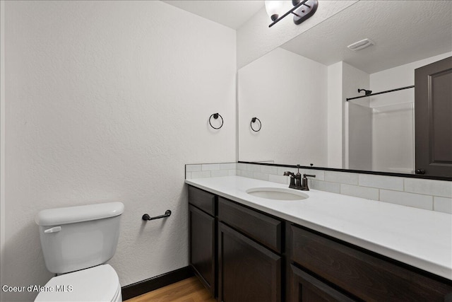 full bathroom with decorative backsplash, visible vents, wood finished floors, vanity, and toilet