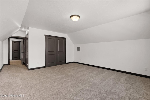 bonus room with baseboards, vaulted ceiling, and light carpet