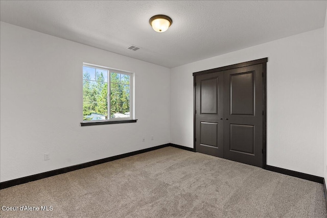 unfurnished bedroom featuring visible vents, a closet, baseboards, a textured ceiling, and carpet flooring