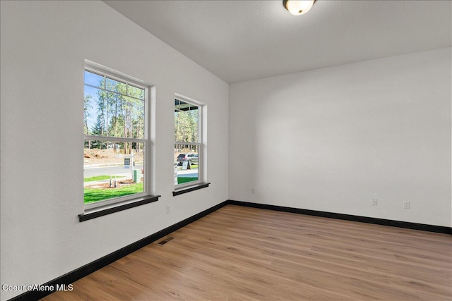 unfurnished room with baseboards, light wood-style flooring, and visible vents