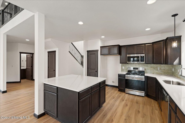 kitchen featuring a sink, appliances with stainless steel finishes, baseboards, and light wood finished floors